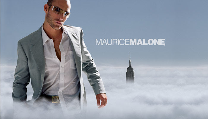 2000s advertising campaign by African-American fashion designer Maurice Malone features a giant, stylish man in a light gray suit and white shirt, partially unbuttoned to reveal a glimpse of his chest.