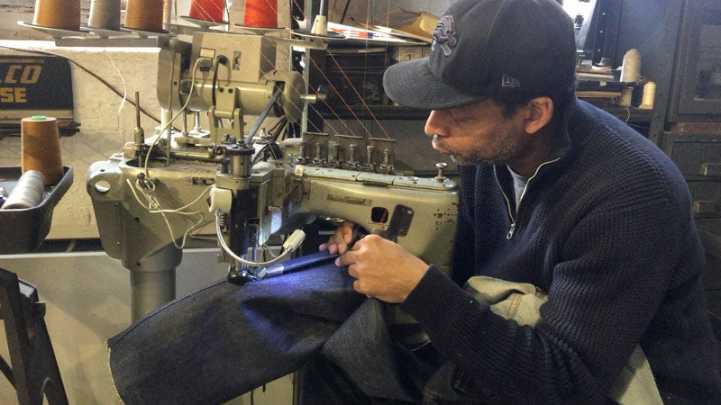 Denim designer Maurice Malone, owner of Williamsburg Garment Company, sewing a pair of jeans with a Union Special 35800 industrial sewing machine in the tapering alterations process.