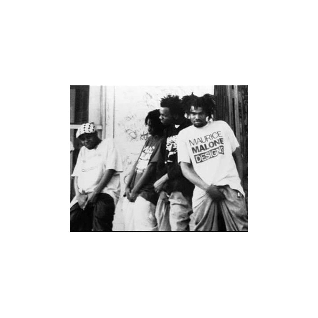 Proof, J Dilla, Thyme of 5-Ela, and possibly Baatin of Slum Village outside The Hip-Hop Shop in Detroit during the 1990s, wearing Maurice Malone t-shirts and striking playful hip-hop poses.