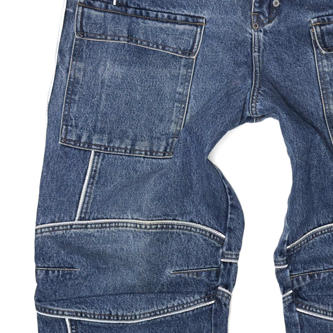 Close-up of 1999 Mojeans Blade Runner jeans front featuring cargo thigh pocket, reflective piping, branded fly tab, and vintage 90s hip hop denim construction.