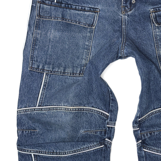Close-up of 1999 Mojeans Blade Runner jeans front featuring cargo thigh pocket, reflective piping, branded fly tab, and vintage 90s hip hop denim construction.