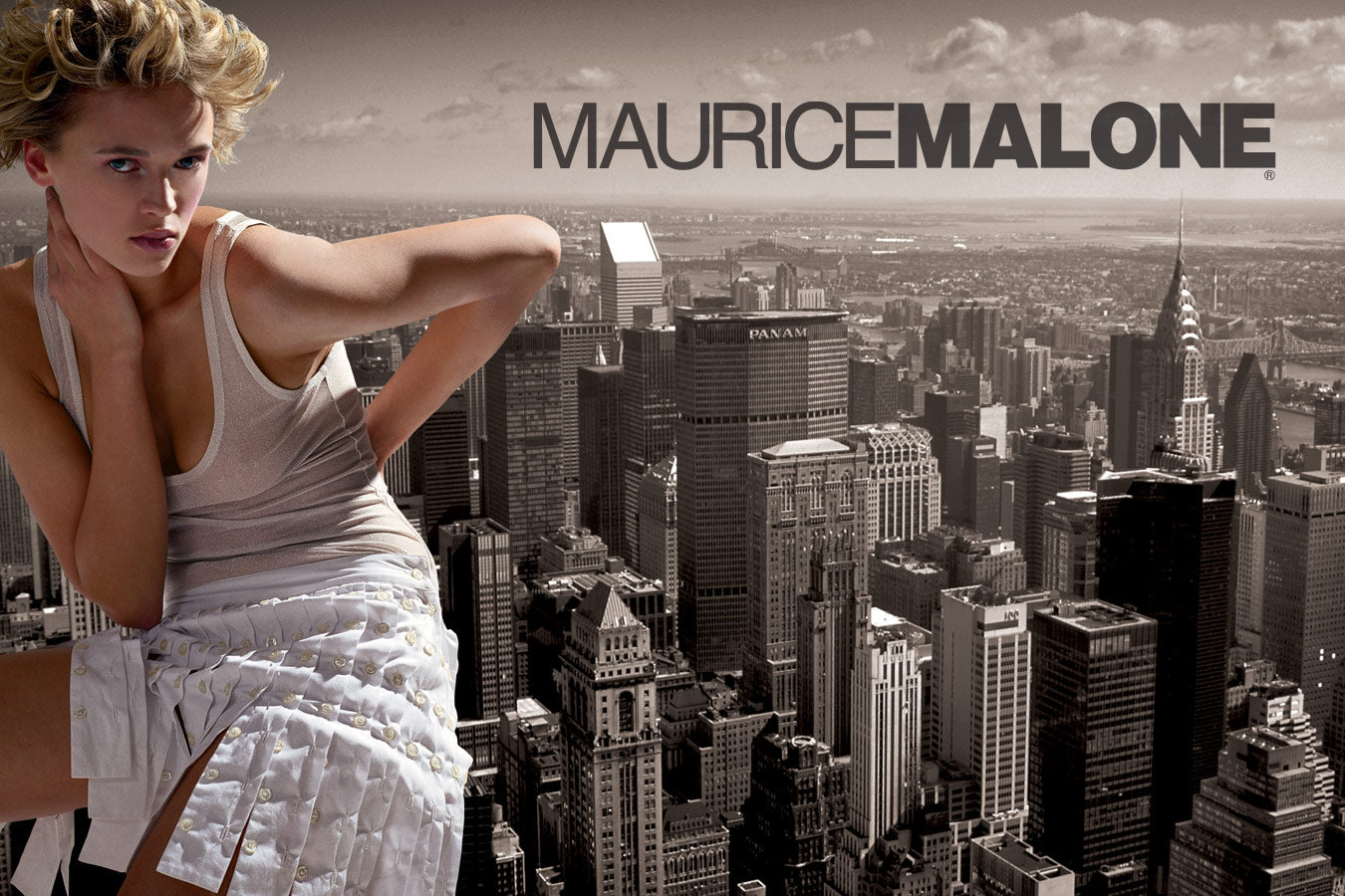 A Maurice Malone advertisement from the early 2000s, where a woman sits on top of a New York City skyscraper. She is dressed in a distinctive white skirt made of working shirt button placket and a shimmering silver tank top, which make her stand out against the urban scene.