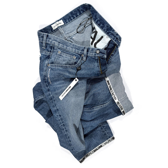 Folded Maurice Malone 1998-BR jeans showing Logo Cuff hem, branded pocket bags, vintage buttons and rivets, and light stonewash denim.