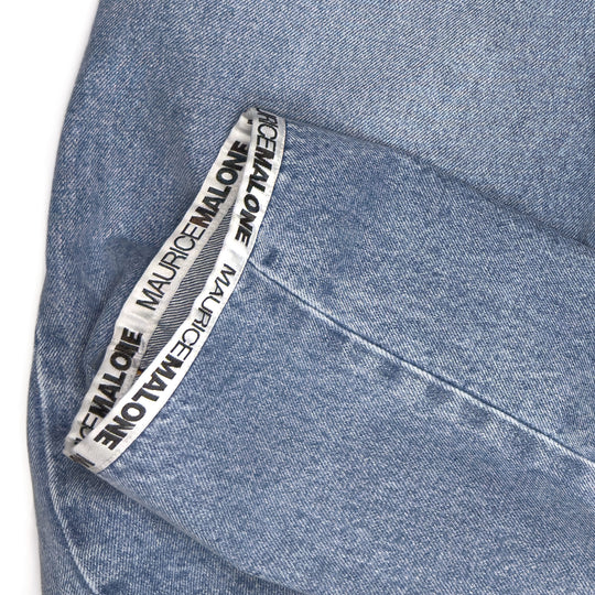 Close-up of Maurice Malone logo tape stitched into the hem of the 2026 Logo Cuff jeans, showing clean black-and-white branding.