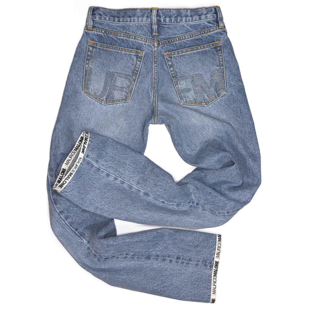 Rear view of Maurice Malone 2026 Logo Cuff jeans in light stonewashed denim, showing tonal “UR” and “EM” embroidery on back pockets stitched in Japanese indigo thread, with logo cuff hem.